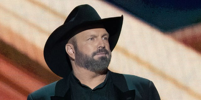 Garth Brooks performs earing signature black hat and coat