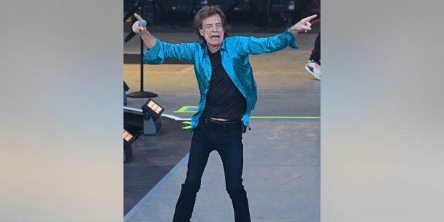 Mick Jagger in Berlin performing with the Rolling Stones pointing in opposite directions on stage