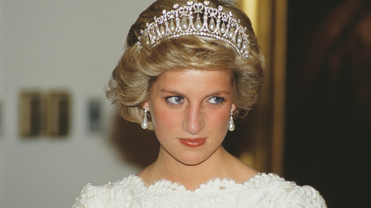 Princess Diana wearing the lovers knot tiara in a white dress looks off camera