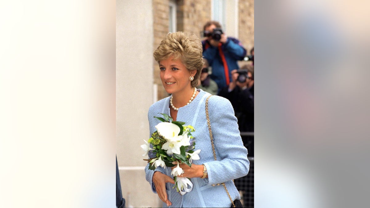 Princess Diana wearing a powder blue suit while holding white flowers