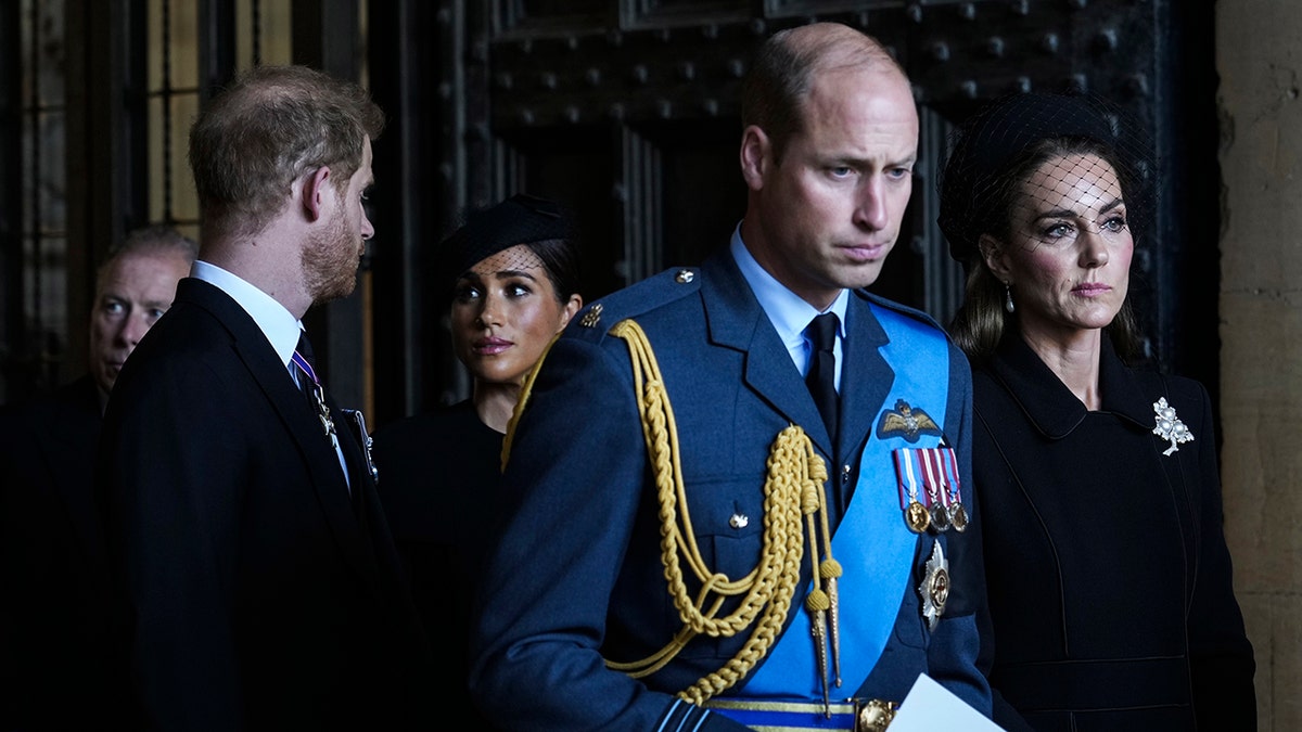 Prince William, Kate Middleton looking somber as Prince Harry and Meghan Markle look at each other.