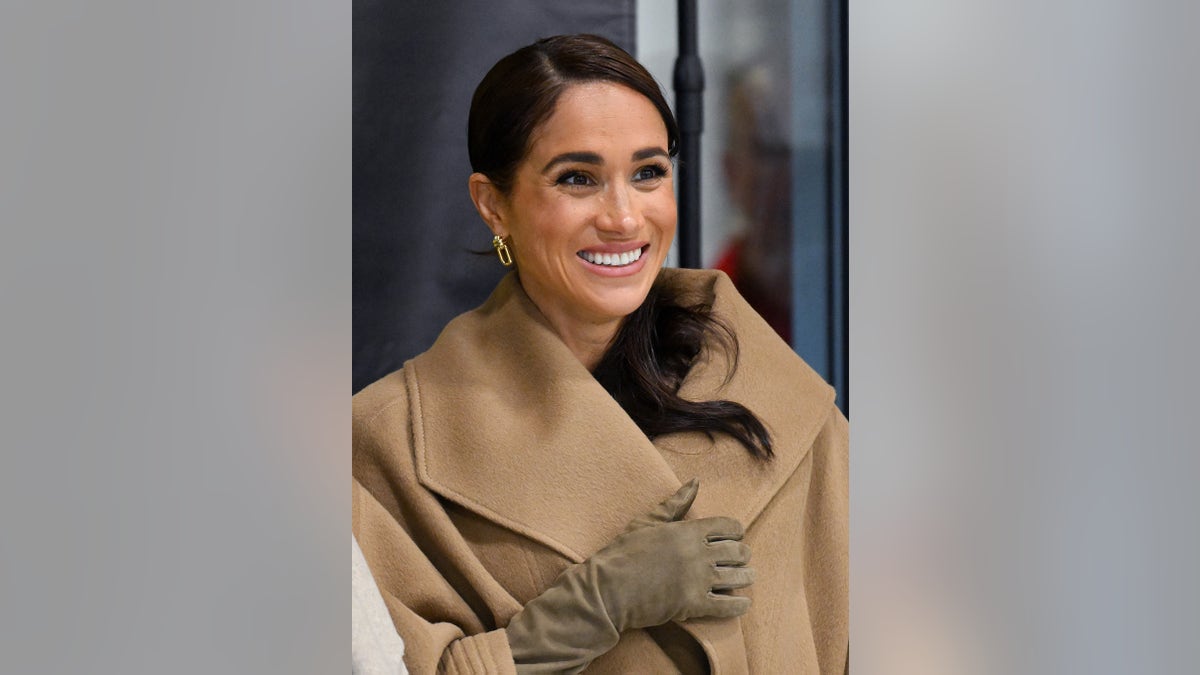 Meghan Markle smiling in a beige coat