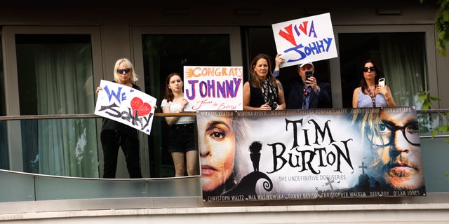 Fans hold signs in support of Johnny Depp at the Cannes Film Festival, with slogans saying "Viva Johnny" and "Congrats Johnny"