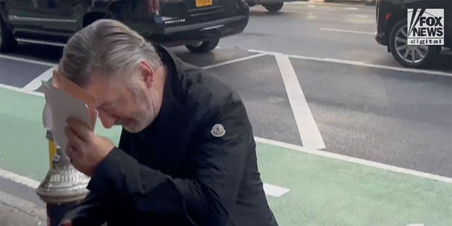 Man in rain jacket attempts to hide his face