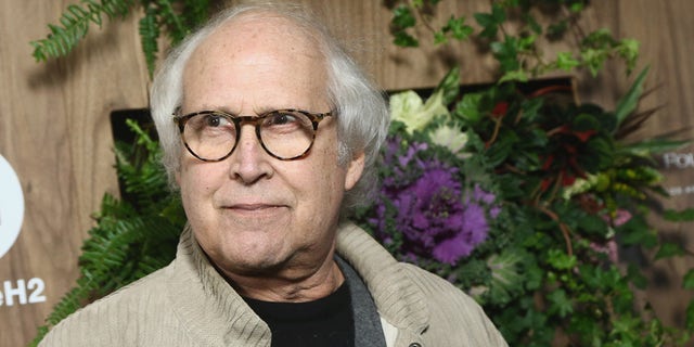 Chevy Chase wears khaki jacket over black T-shirt