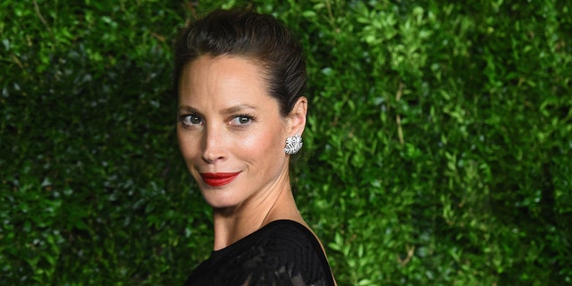 Model Christy Turlington wearing a black dress and red lipstick