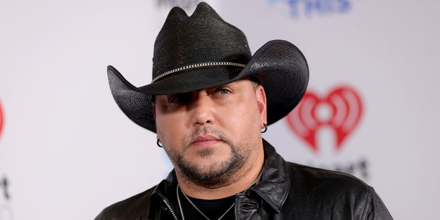 Jason Aldean looks off in the distance wearing a black cowboy hat