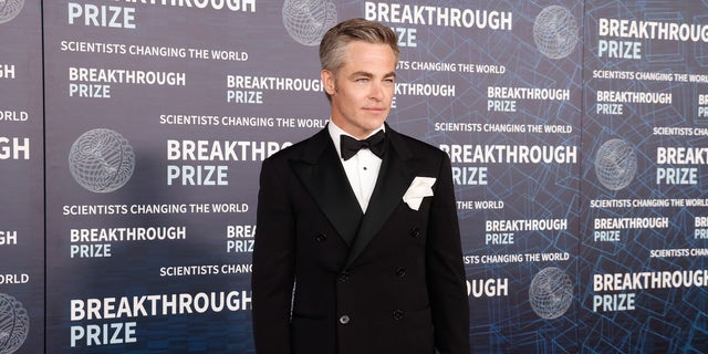 Chris Pine in a tuxedo on a red carpet.