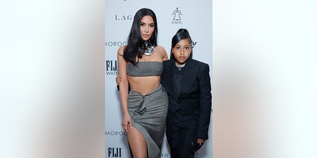 Kim Kardashian in gray two piece with North West in black suit