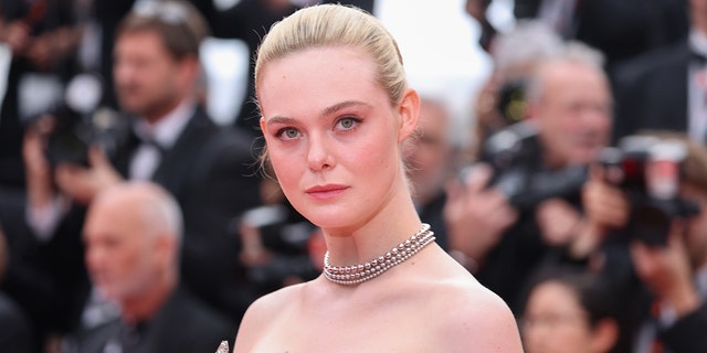 Elle Fanning smizes on the red carpet in Cannes wearing a strapless dress and a chain necklace