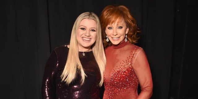 Kelly Clarkson in dark red sequins with Reba McEntire in sheer red dress