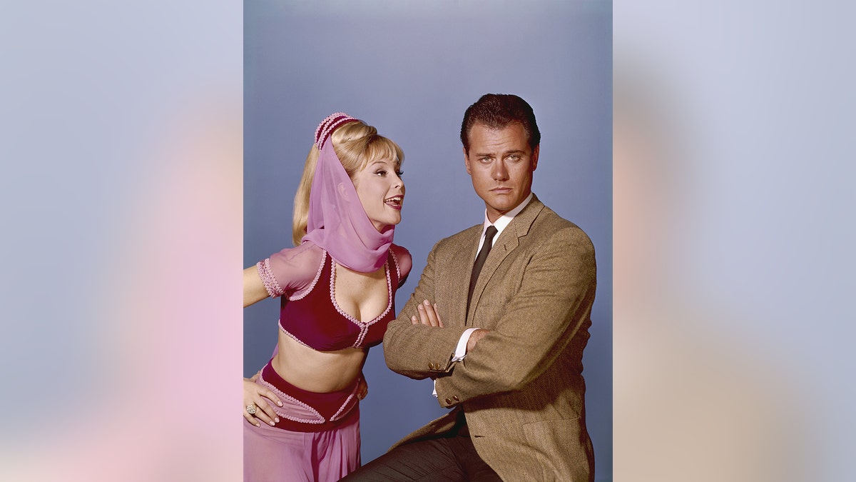 Barbara Eden making a funny face to Larry Hagman as she looks annoyed.