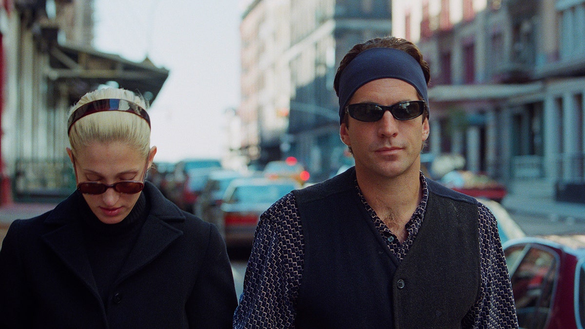 John F. Kennedy Jr. looks annoyed as Carolyn Bessette-Kennedy looks down outside in New York City.