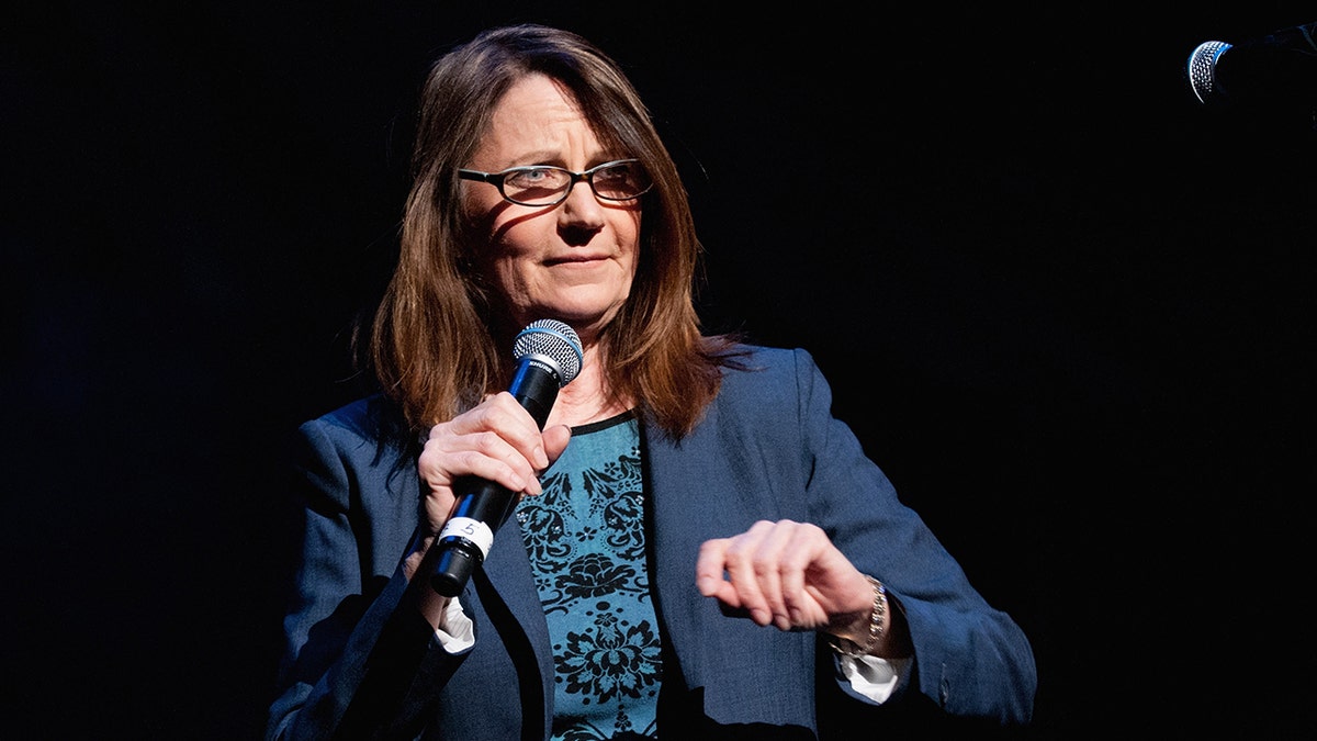 Judy Belushi-Pisano on stage with a microphone