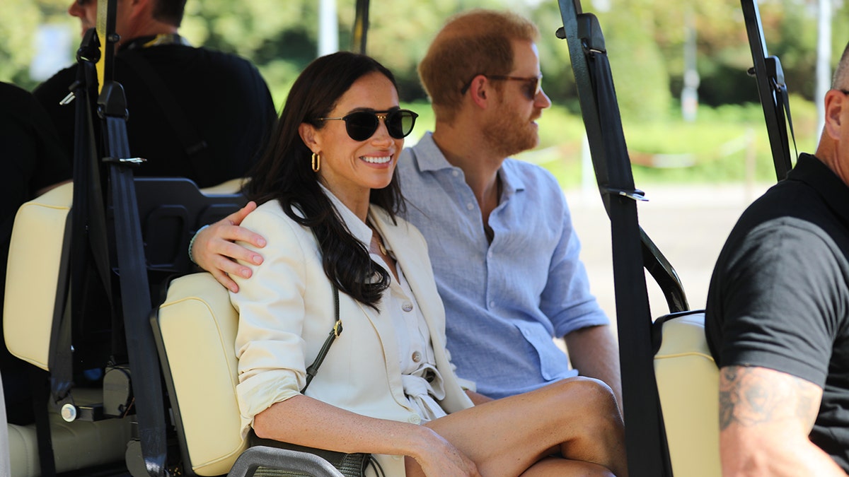 Prince Harry and Meghan Markle ride in a golf cart