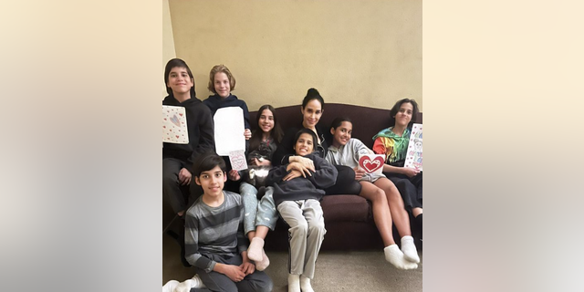 Nadya Suleman sits on the couch with seven of her kids, several holding cards for Mother's Day