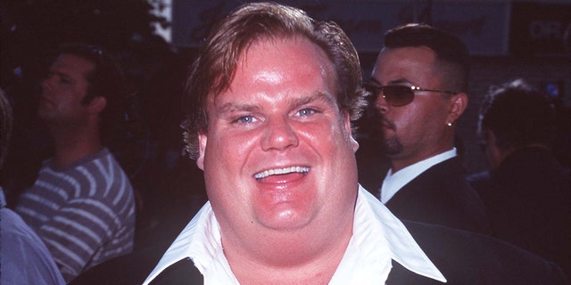 Chris Farley smiles while walking red carpet