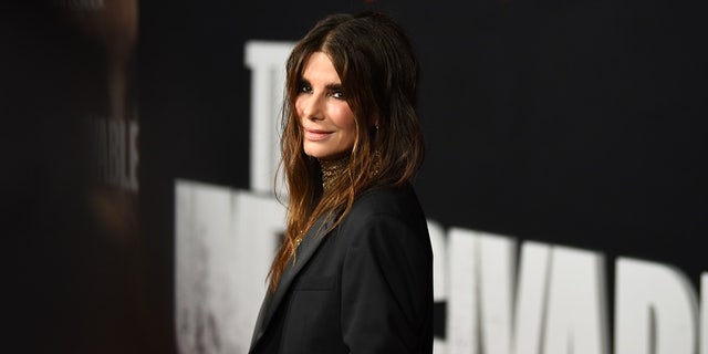 Sandra Bullock looks slightly over her shoulder in a black outfit on the carpet 