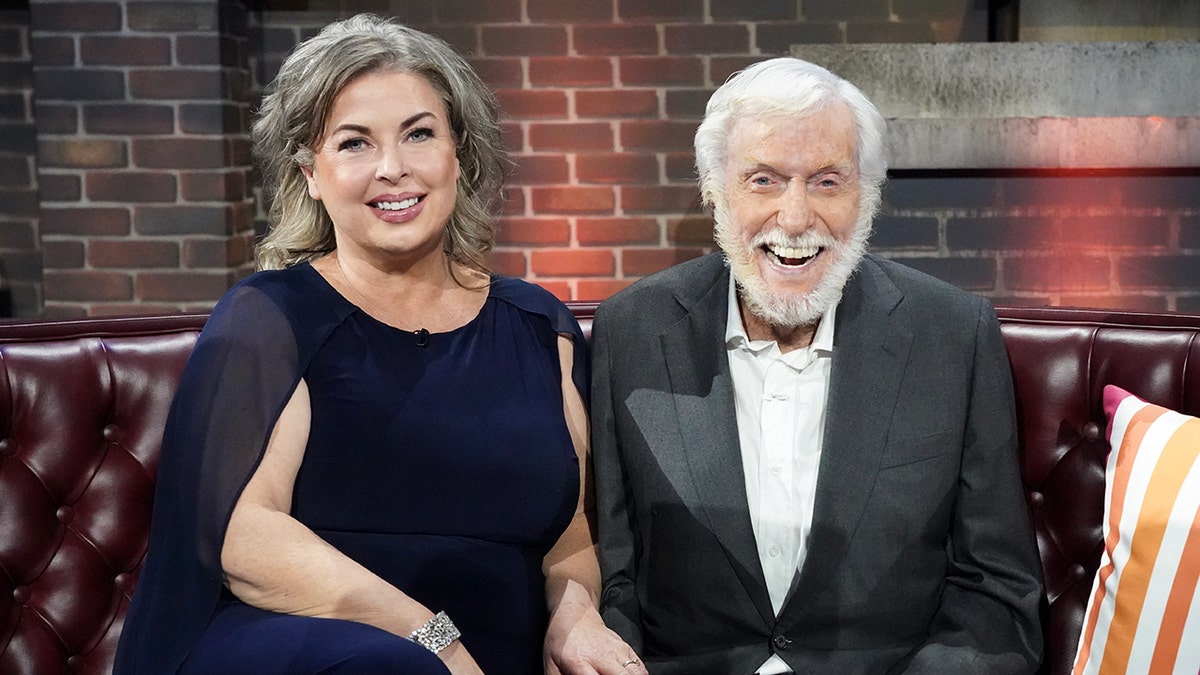 Arlene Silver in a navy cut-out dress smiles with husband Dick Van Dyke in a classic black tuxedo