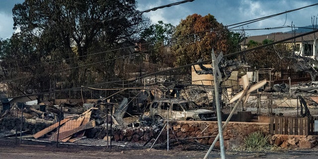 A picture of the devastation across Lahaina, Hawaii with rubble behind a chained fence