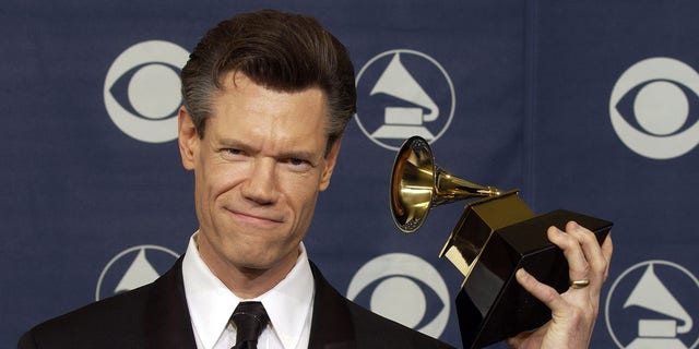 A photo of Randy Travis posing with his Grammy Award in 2004