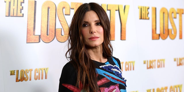 Sandra Bullock in a black dress with many color swatches on the front at "The Lost City" premiere